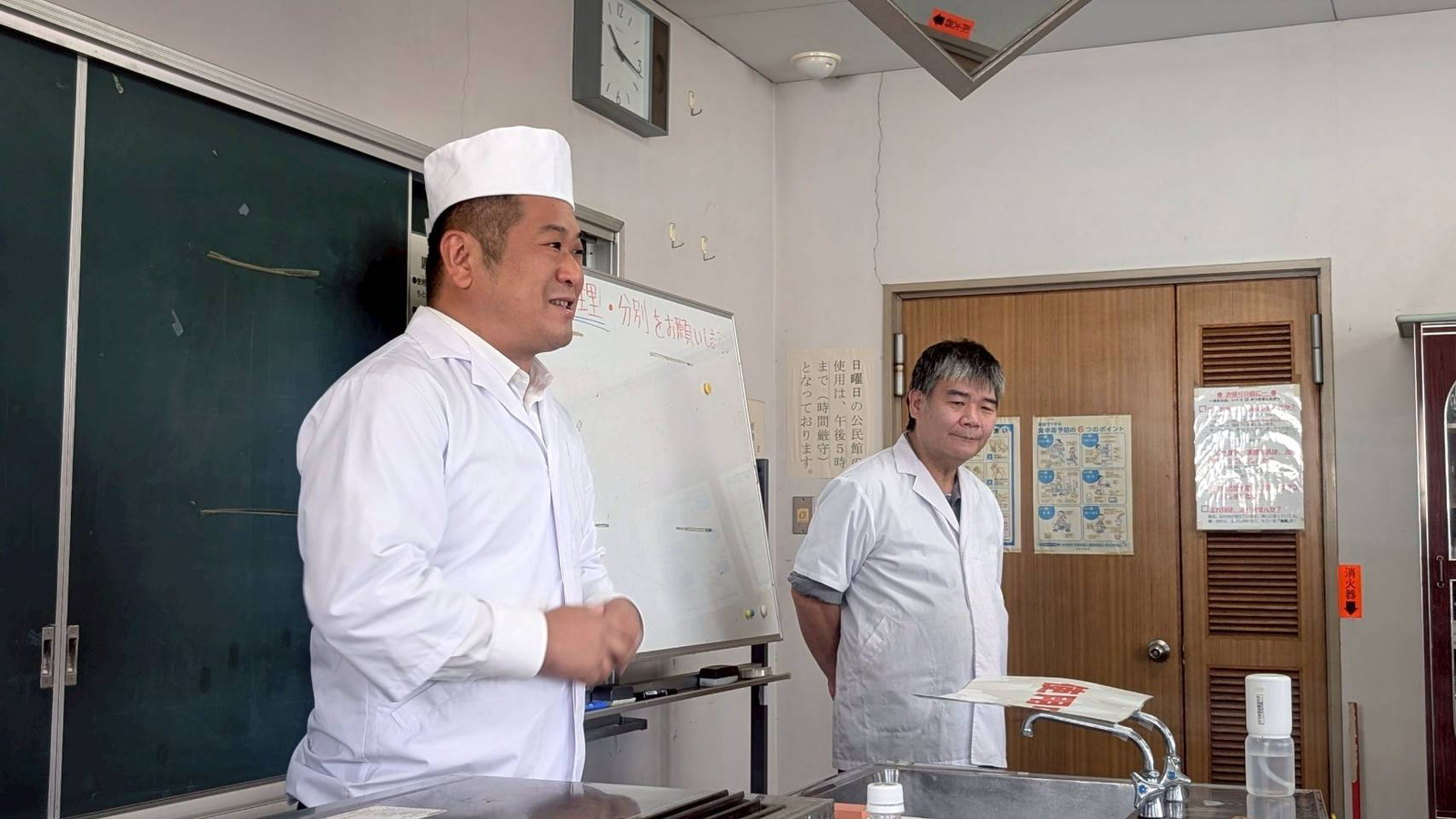 白い調理服と帽子姿で挨拶する会長